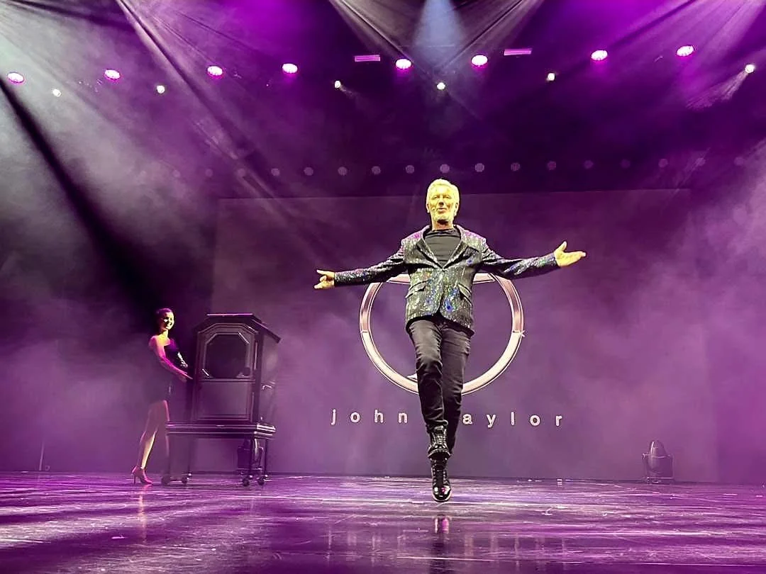 John Taylor performing under theatrical stage lights