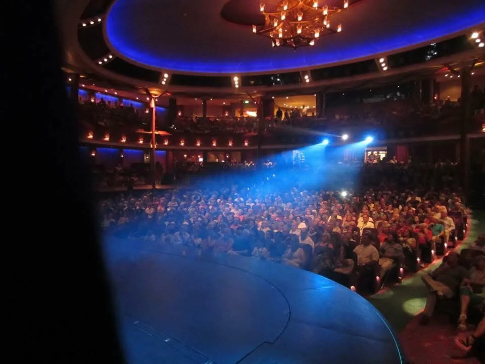 A large theatre auditorium with a curved stage and seated audience